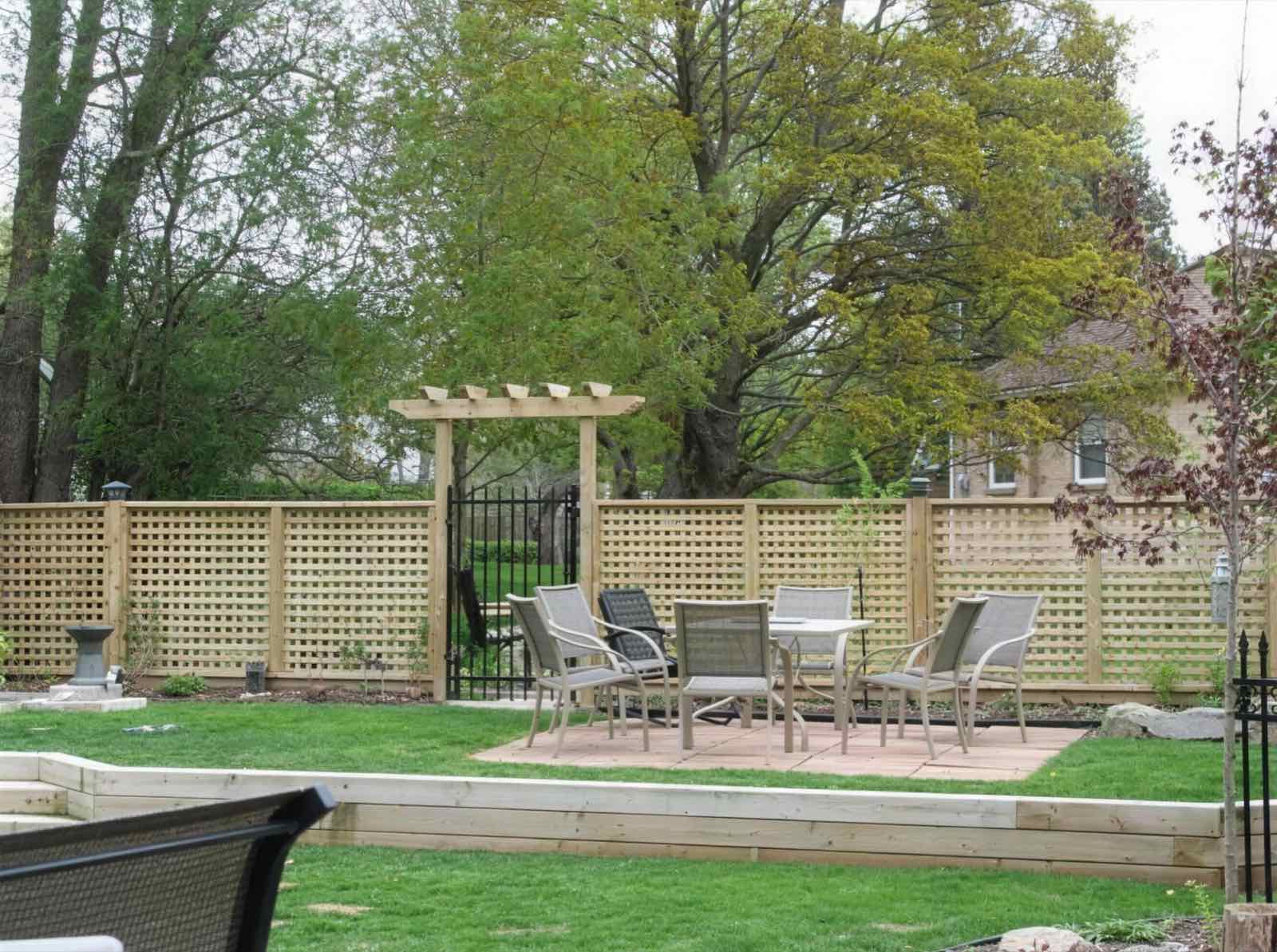 Lattice wood screen with an arched entry around a backyard patio